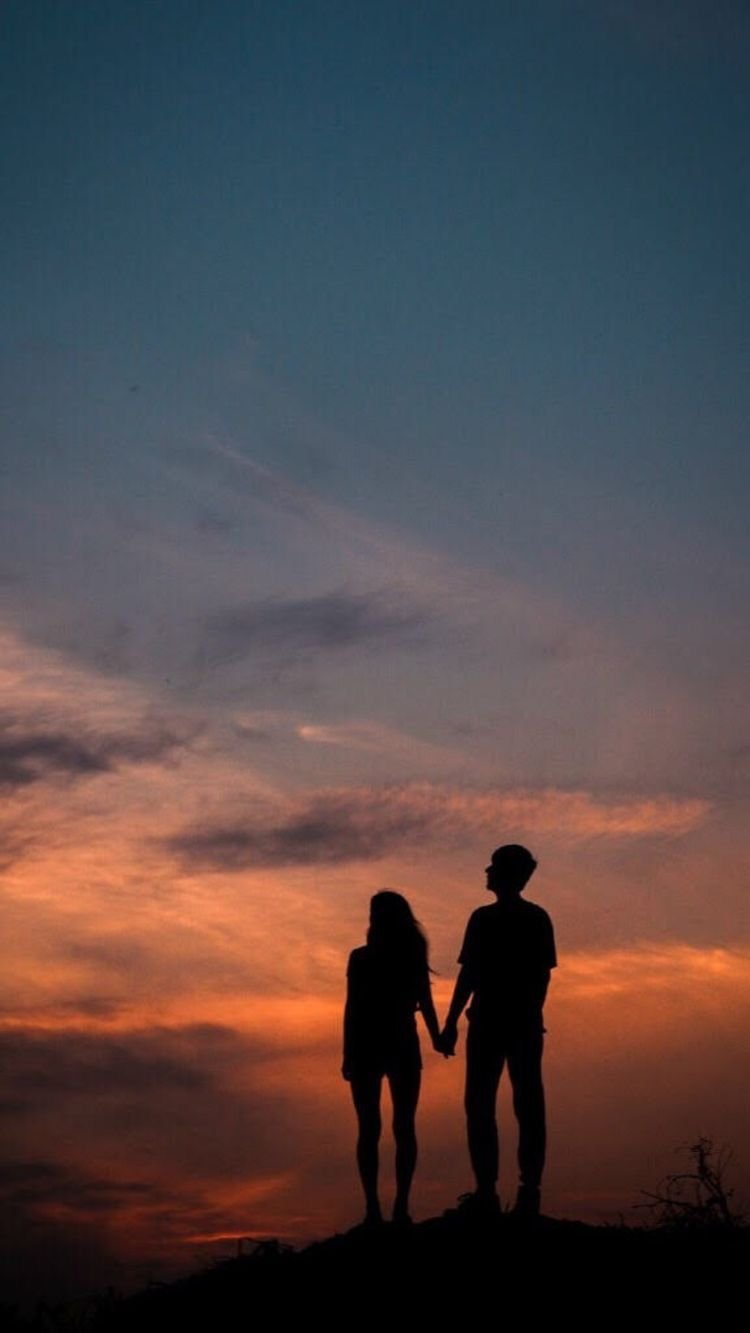 couple holding hands silhouette sunset